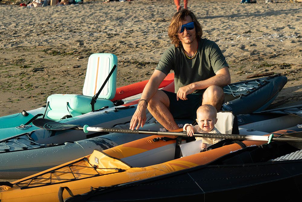 a father and baby sitting in a series of inflatable kayaks