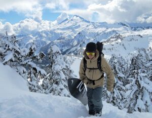 a snowboarder hikes on the shuksan arm with mount baker in the background